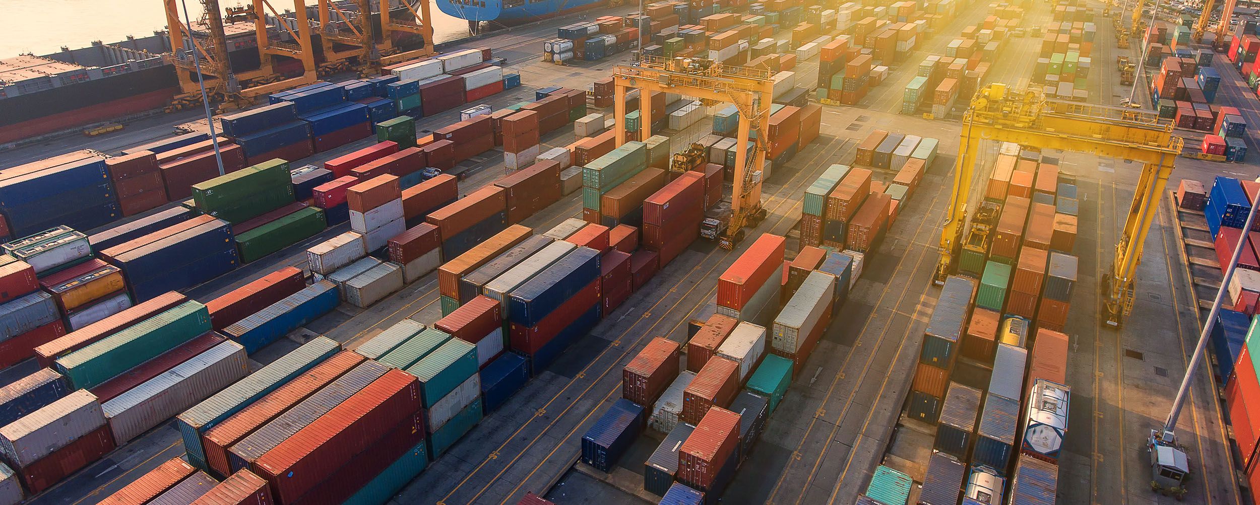 Luftaufnahme eines Containerhafens mit zahlreichen Containern, die ordentlich in Reihen angeordnet sind